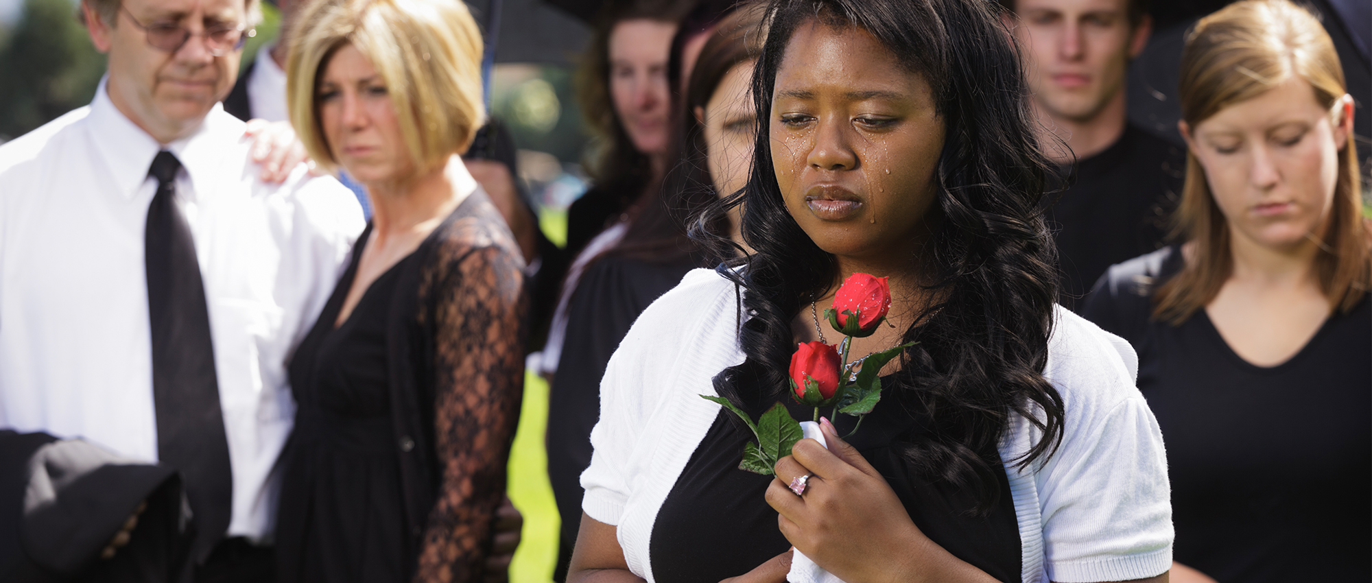 Woman mourns next to casket during ceremony.