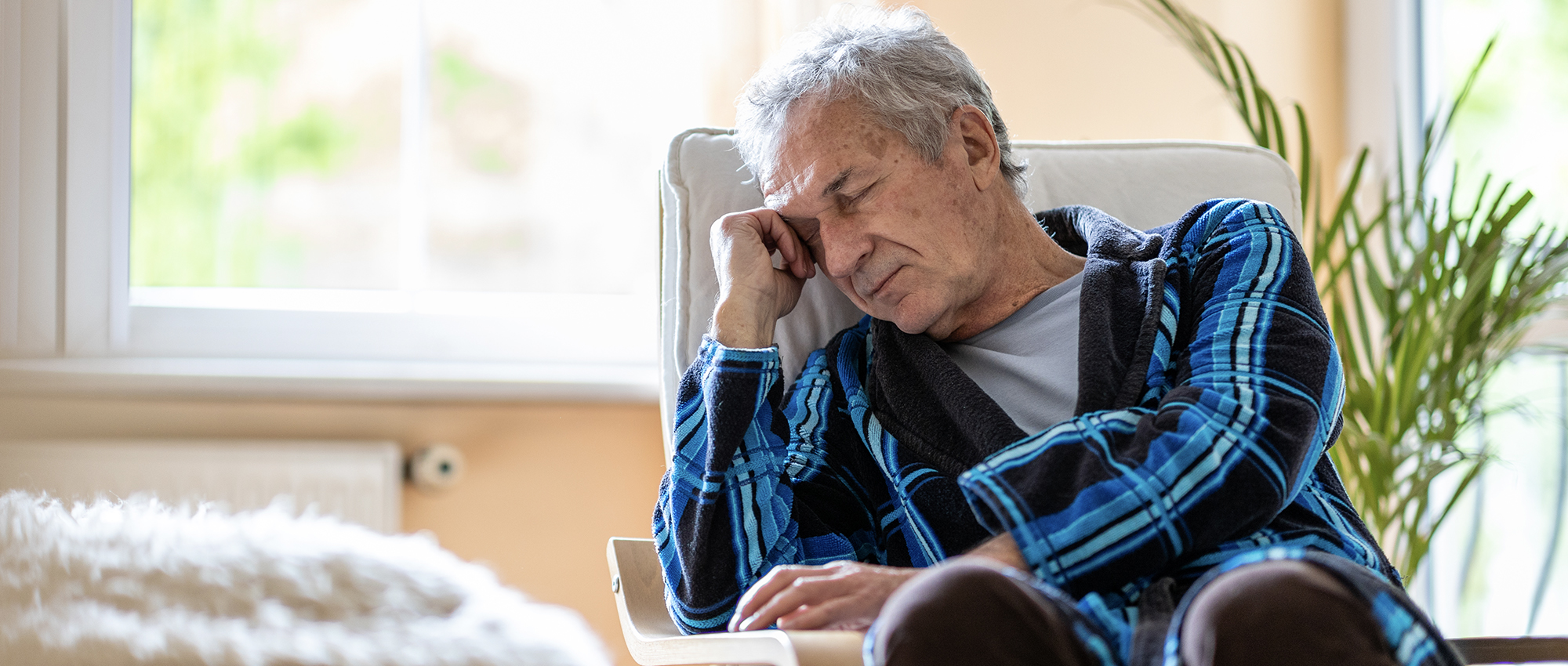 Elder person falls asleep in chair alone in a nursing home.