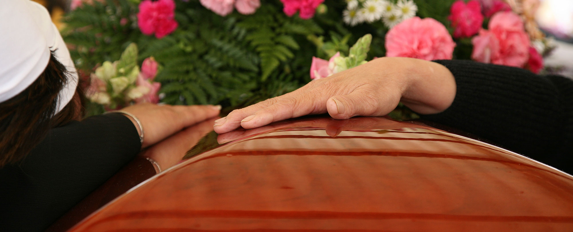 hand on coffin with flowers during daytime funeral