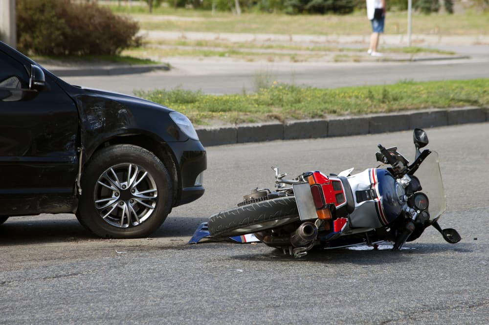 A motorcycle lies on its side after a collision with a car, illustrating common biases against motorcyclists in accidents.