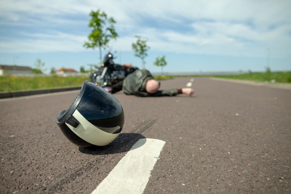 A biker helmet lies on street near a motorcycle accident.