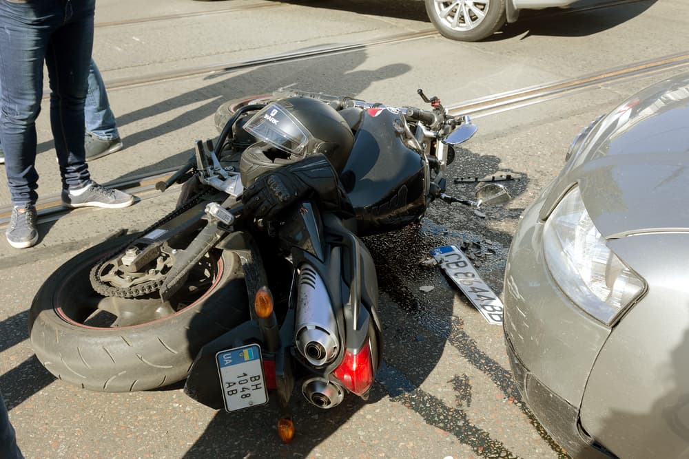 Car and motorcycle collision on wet asphalt. First aid, police, and insurance agent on the scene. Accident aftermath.
