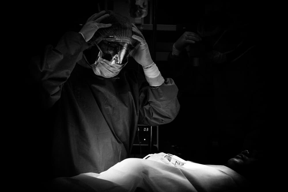 Surgical team addressing challenges in the operating room. Professional medical setting captured in a subdued, dark ambiance.