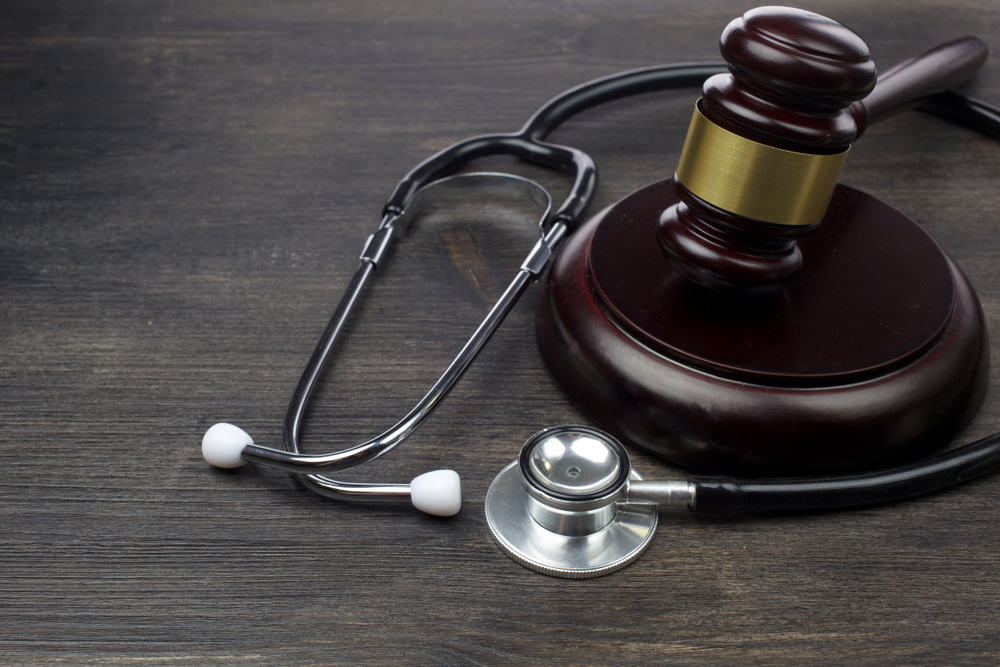 An image depicting a premises liability lawyer: a gavel and scales of justice beside a blueprint on a wooden desk.