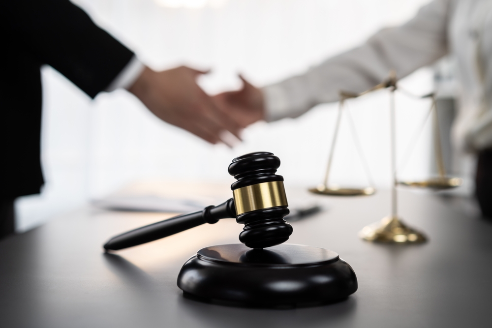 Lawyer colleagues shaking hands after successfully resolving a lawsuit in court, advocating for dispute resolution.