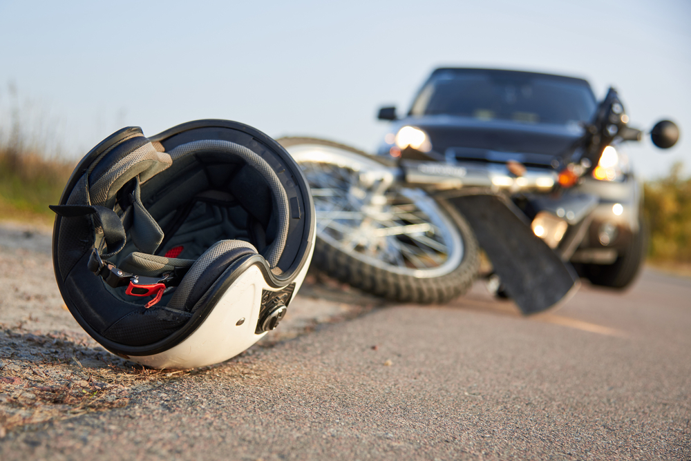 Photo of a car, a helmet, and a motorcycle on the road, illustrating the concept of road accidents