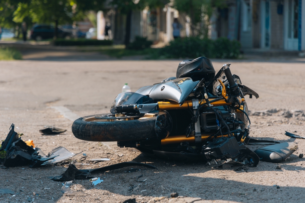 The motorcycle lies on the road after a severe collision. Close-up of the accident scene showing the damaged bike. Traffic accident