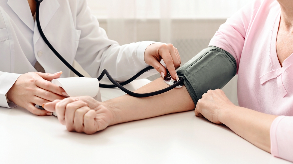 A doctor in a white coat carefully examines a patient's arm while drawing blood for a medical test. The patient appears calm and focused throughout the procedure.