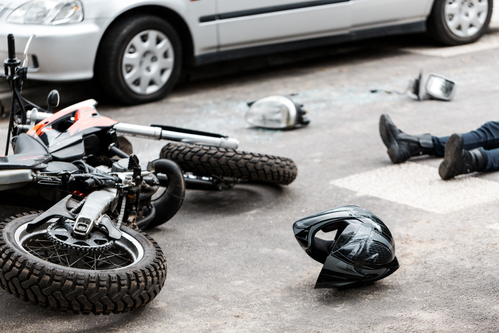 Legs of a person lying on the road following a motorcycle and car collision