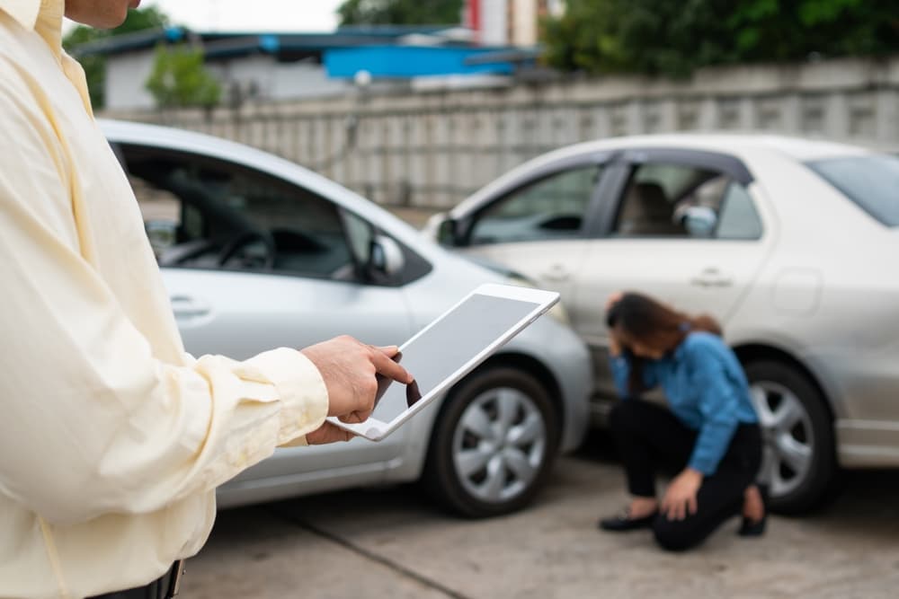 Insurance adjuster taking a photo with a smartphone to send evidence for a car accident claim. Concept of submitting claims online.