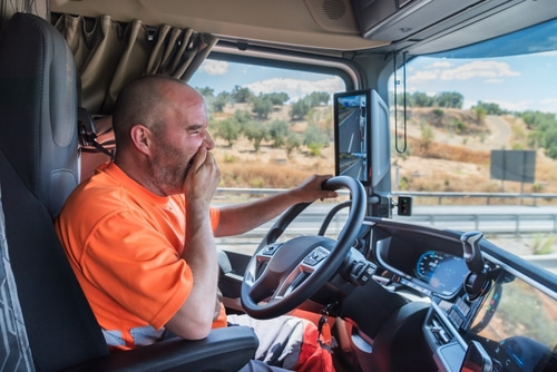 a tired truck driver yawning behind the wheel, representing the importance of identifying multiple liable parties in a truck accident case