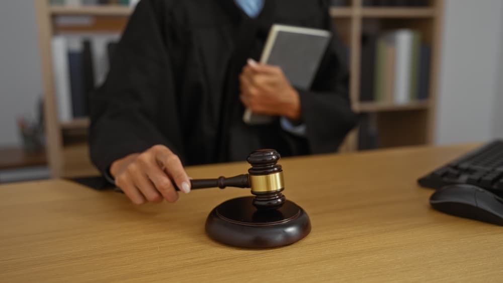 Judge holding gavel and book in courtroom, ready to make a judgement, 