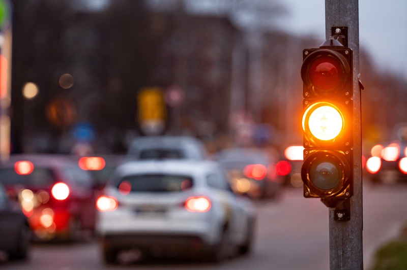 city crossing with a semaphore on blurred background with cars in the evening streets, orange light