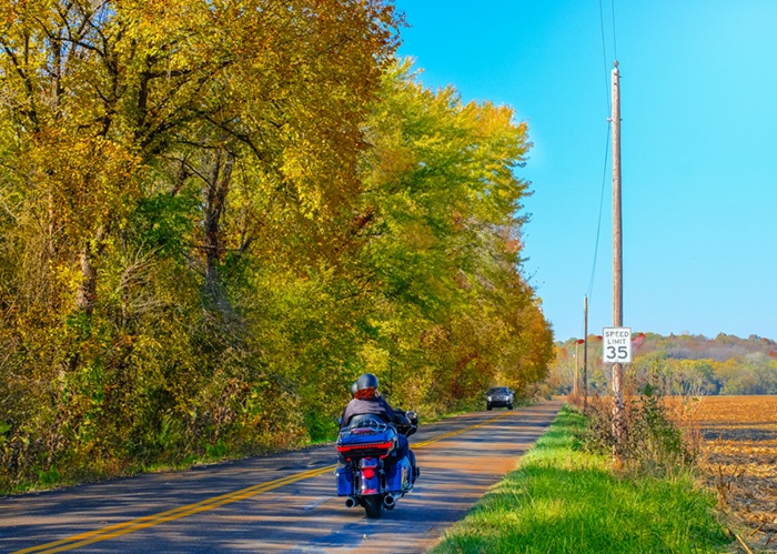A motorcycle riding down a peaceful country road.