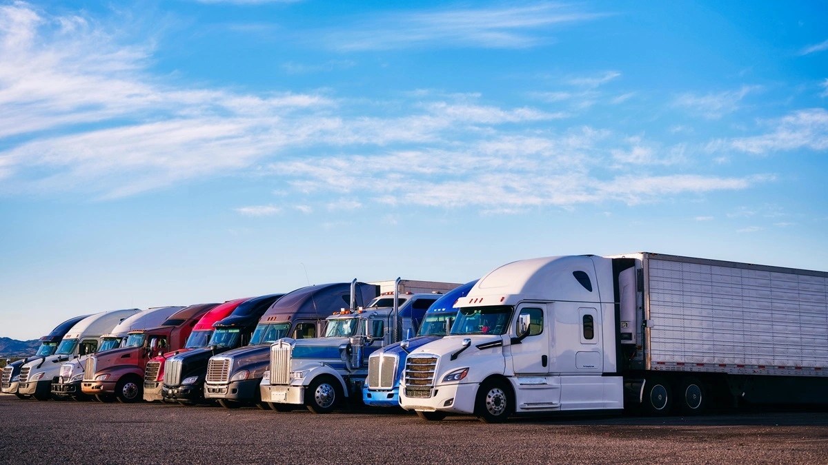 A line of semi trucks parked together in a parking lot.