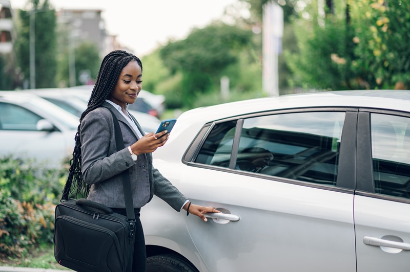 A woman getting into the back of a rideshare vehicle