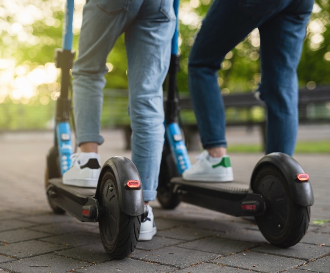 Mother and daughter riding electric scooters in city park